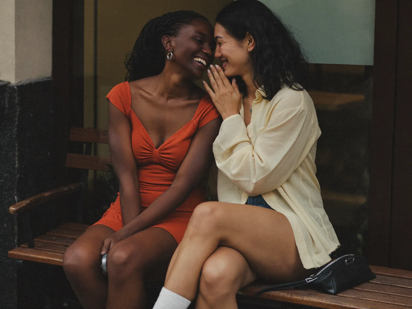Two women sitting close together on a bench.