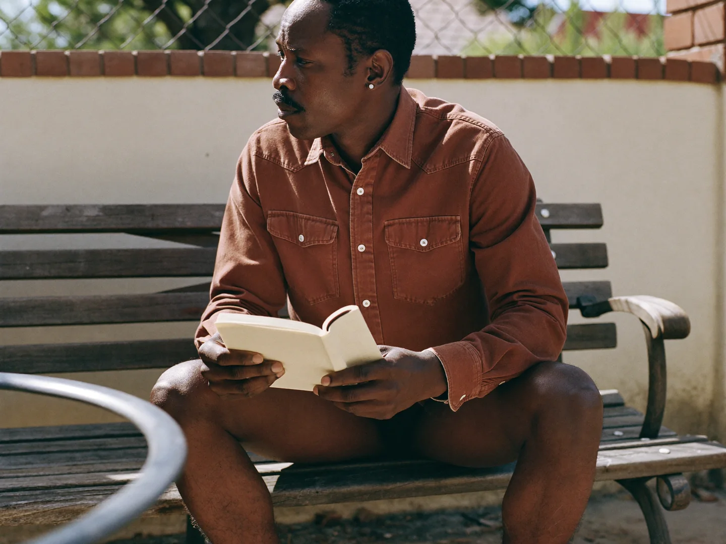 A man seated outdoors with a notebook.
