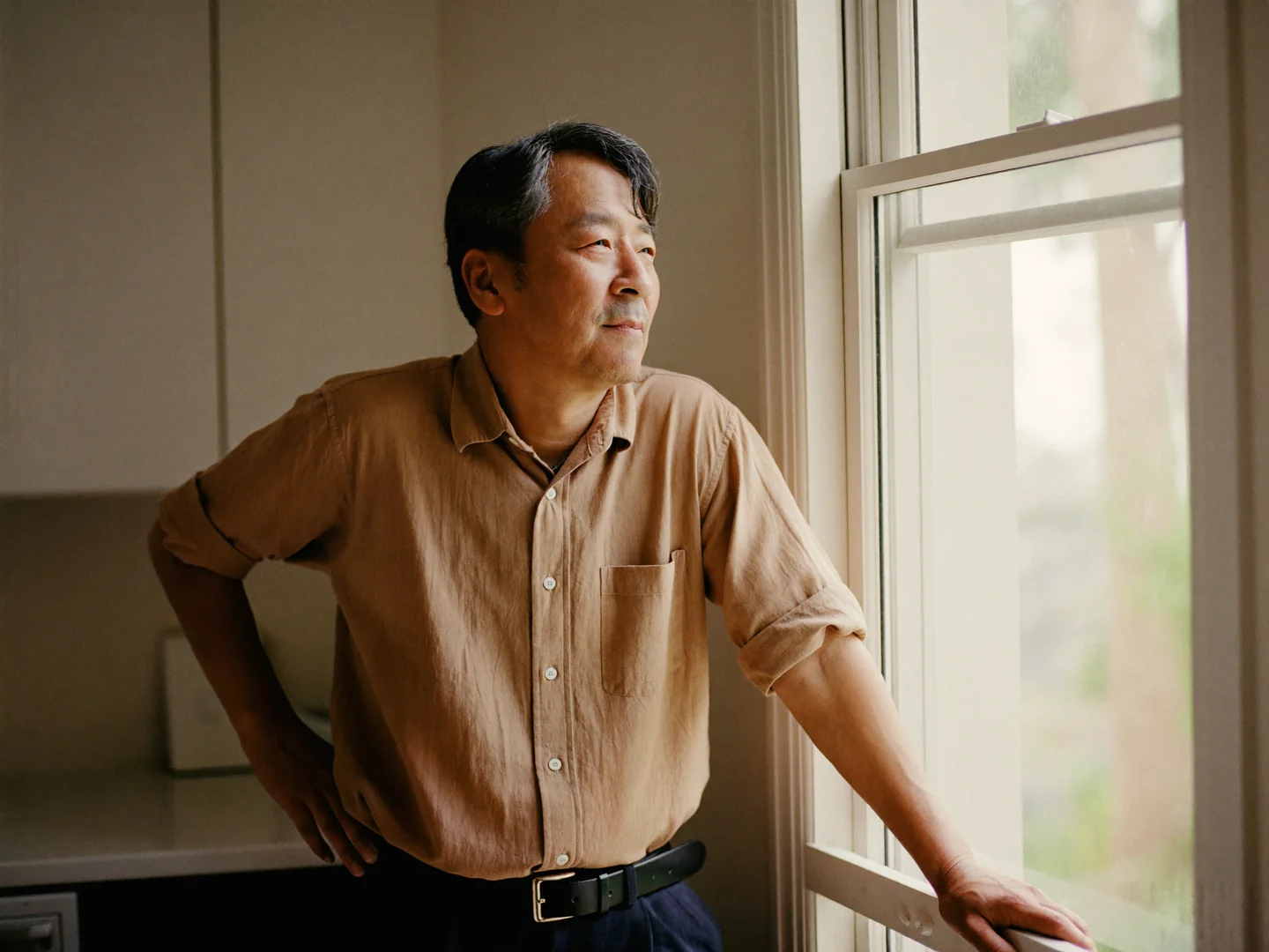 A man standing beside a bright kitchen window.