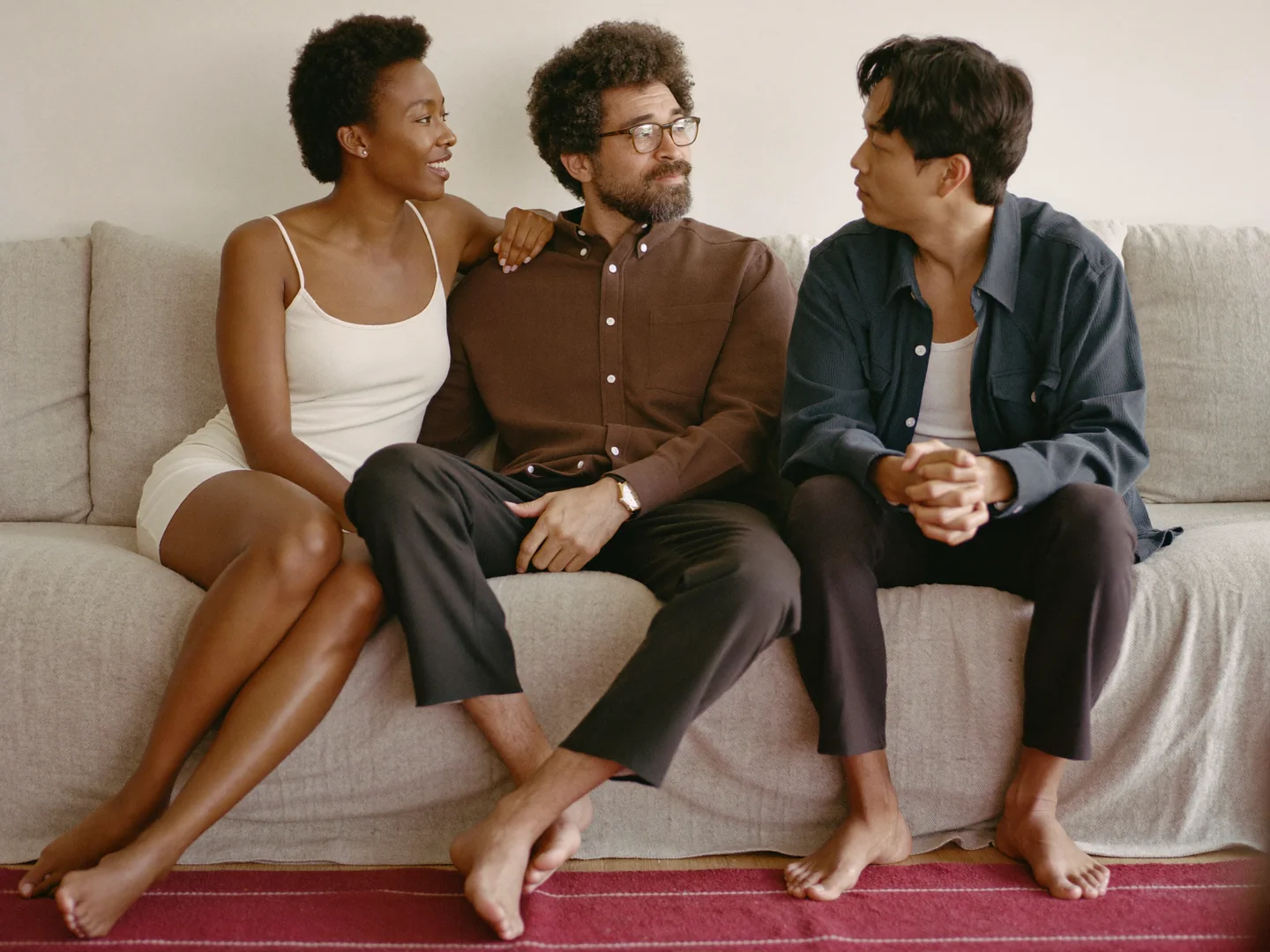 Three adults talking together on a sofa.