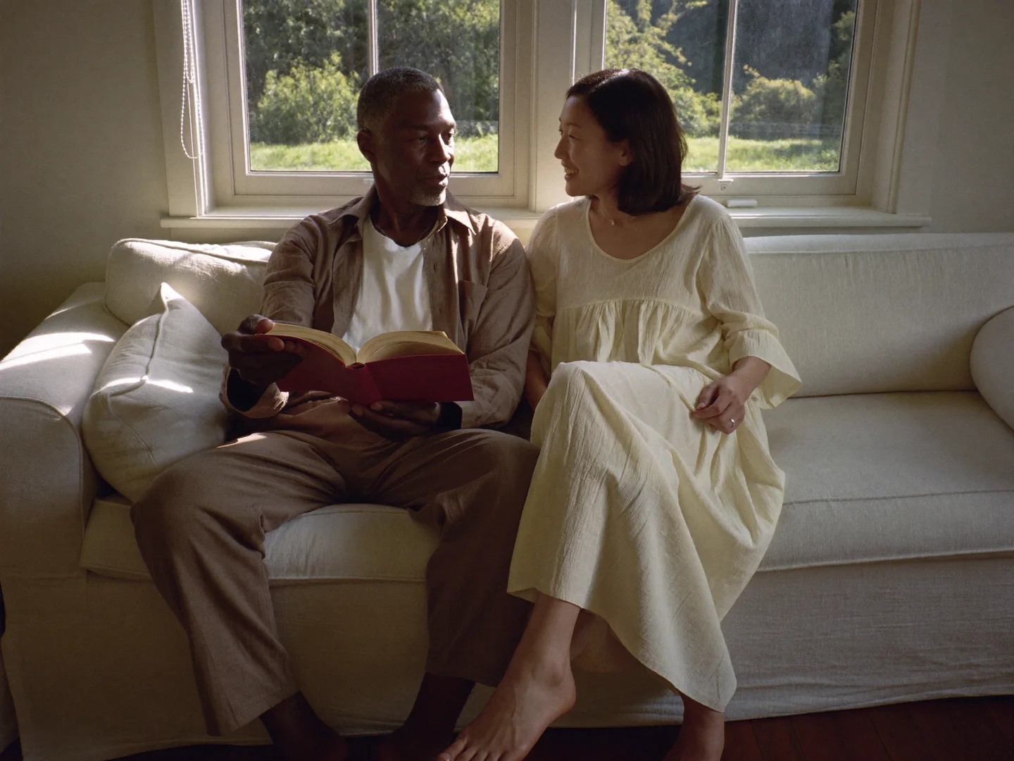 A man and woman reading and talking together on a sofa.