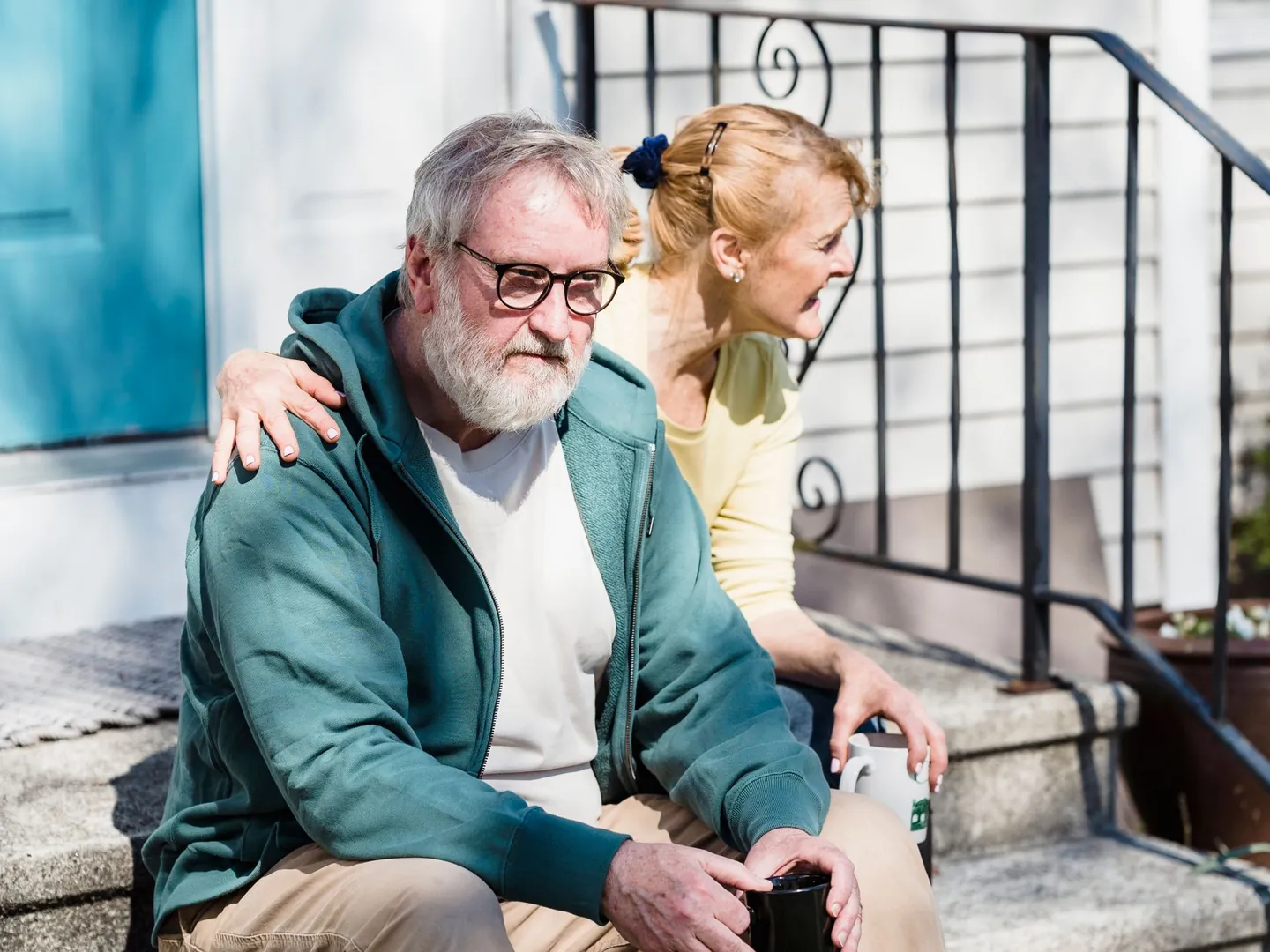A woman and man sitting together on sunlit front steps.